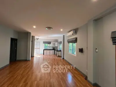 Spacious open-plan living area with wooden flooring and modern kitchen.