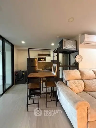Modern living room with open kitchen, featuring cozy sofa and dining area, ideal for urban living.