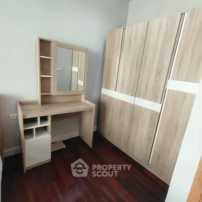 Modern bedroom with sleek wooden wardrobe and matching vanity set on polished hardwood floor.