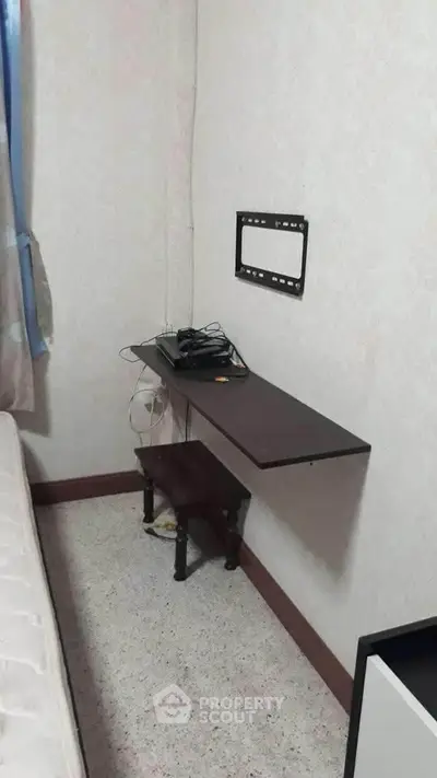 Compact bedroom with wall-mounted desk and small stool, ideal for minimalistic living.