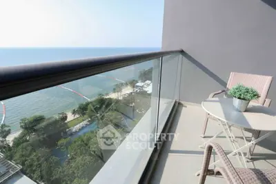 Stunning ocean view from a modern balcony with glass railing and cozy seating area.
