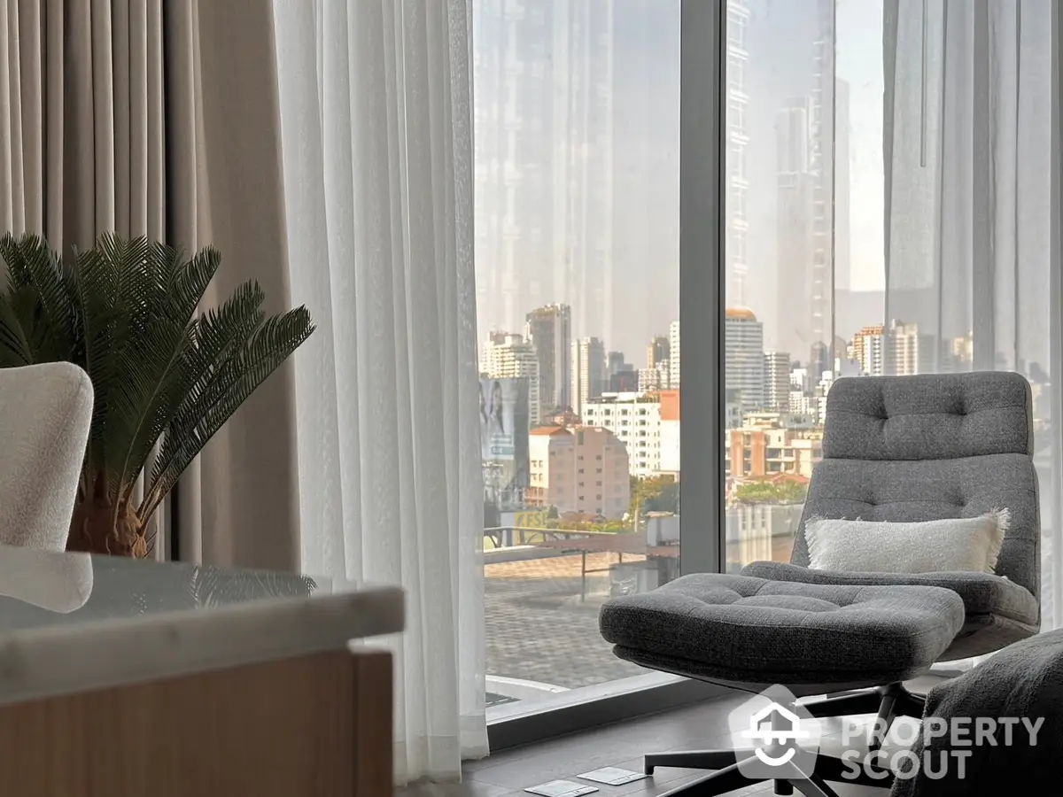 Luxurious corner unit with floor-to-ceiling windows offering panoramic city views, complemented by a modern lounge chair and chic decor.