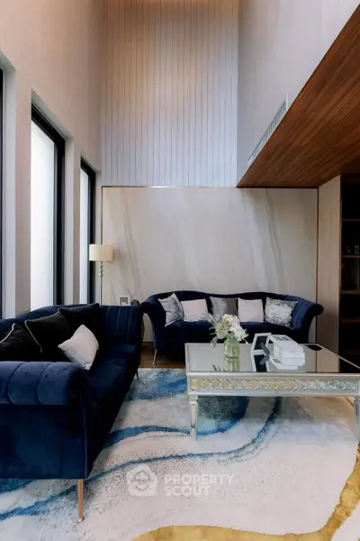 Luxurious living room with high ceilings, elegant blue sofas, and stylish decor in a modern home.