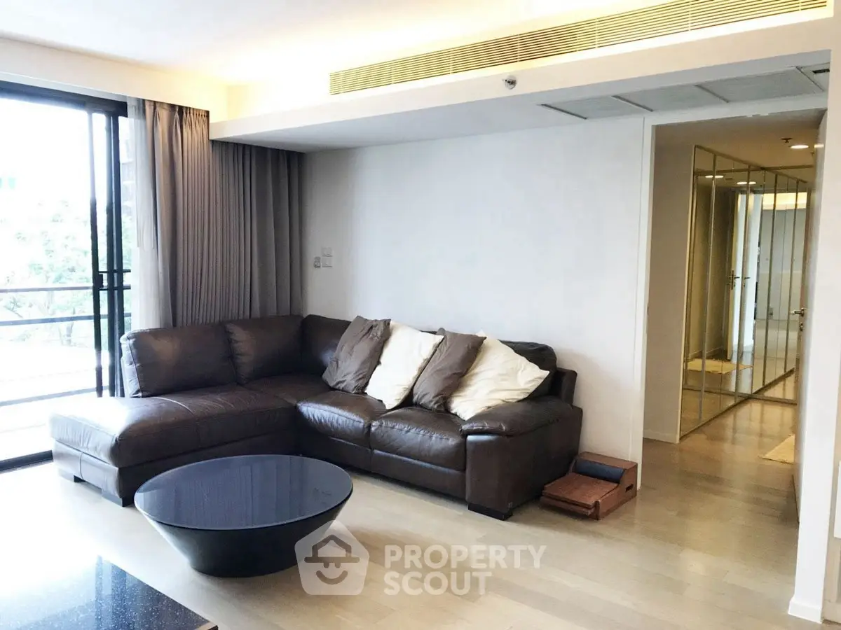 Spacious living room with modern leather sofa and large windows in a stylish apartment.