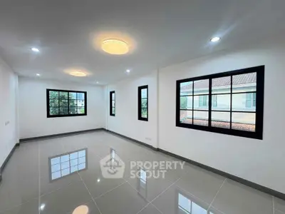 Spacious modern living room with large windows and glossy tiled floors