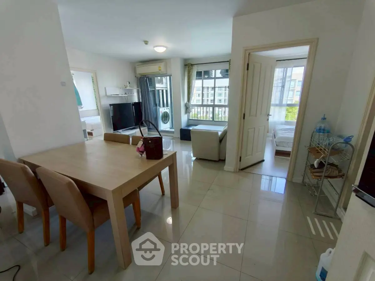 Spacious modern apartment with open living and dining area, featuring large windows and stylish furniture.