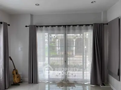 Bright living room with large windows and guitar, perfect for relaxation.