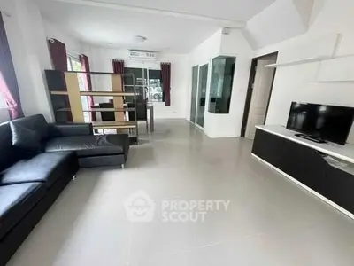 Spacious modern living room with sleek black sofa and wall-mounted TV unit.