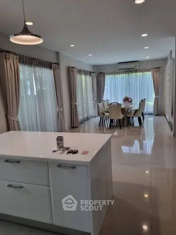 Spacious open-plan living and dining area with modern kitchen island and elegant decor.