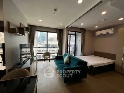 Modern studio apartment with city view, featuring a cozy living area and large windows.