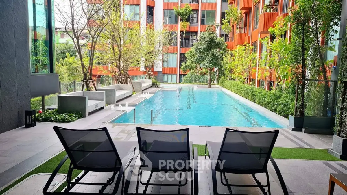 Luxurious apartment pool area with modern lounge chairs and lush greenery