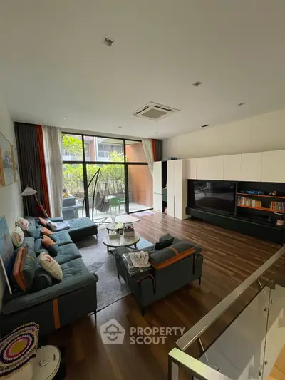 Spacious modern living room with large windows and stylish furniture, perfect for family gatherings.