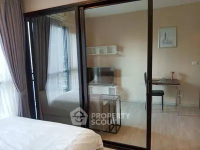 Modern apartment with glass partition separating bedroom and study area, featuring sleek furniture and natural light.