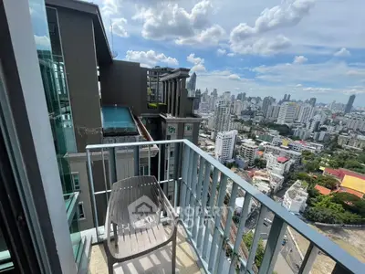 Stunning city view from a high-rise balcony with modern chair and glass railing.