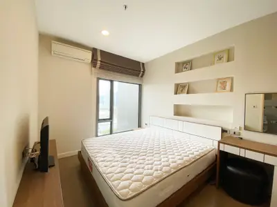 Modern bedroom with large window and minimalist decor in a high-rise apartment.