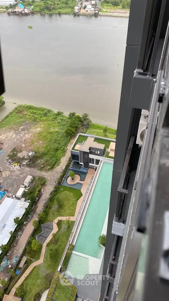Stunning aerial view of modern riverside apartment with pool and lush greenery.