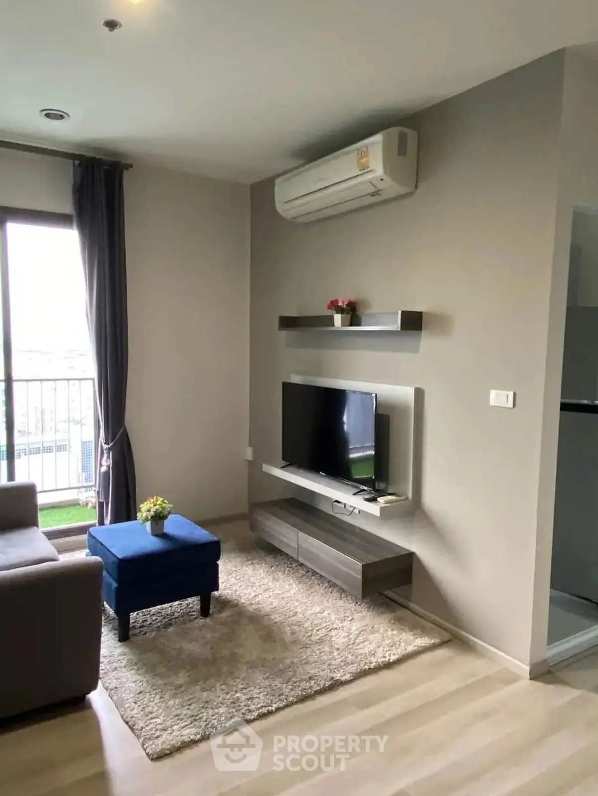 Modern living room with sleek TV setup and air conditioning, featuring a cozy rug and stylish decor.