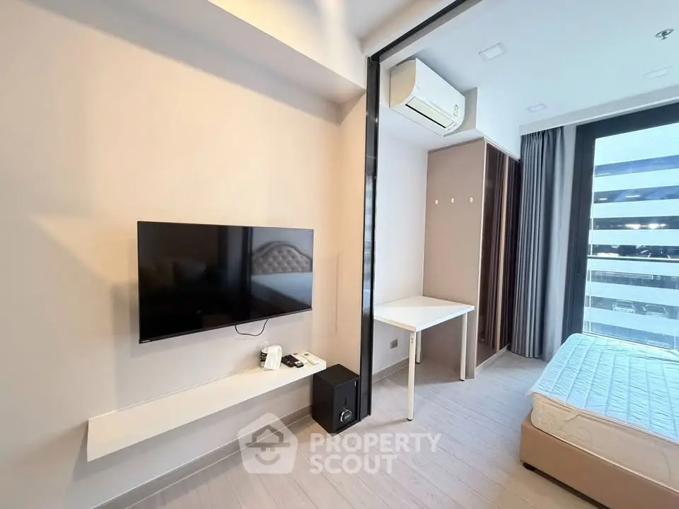 Modern bedroom with wall-mounted TV and air conditioning in a bright apartment