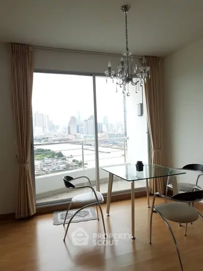 Modern dining area with glass table and city view from large window in high-rise apartment.
