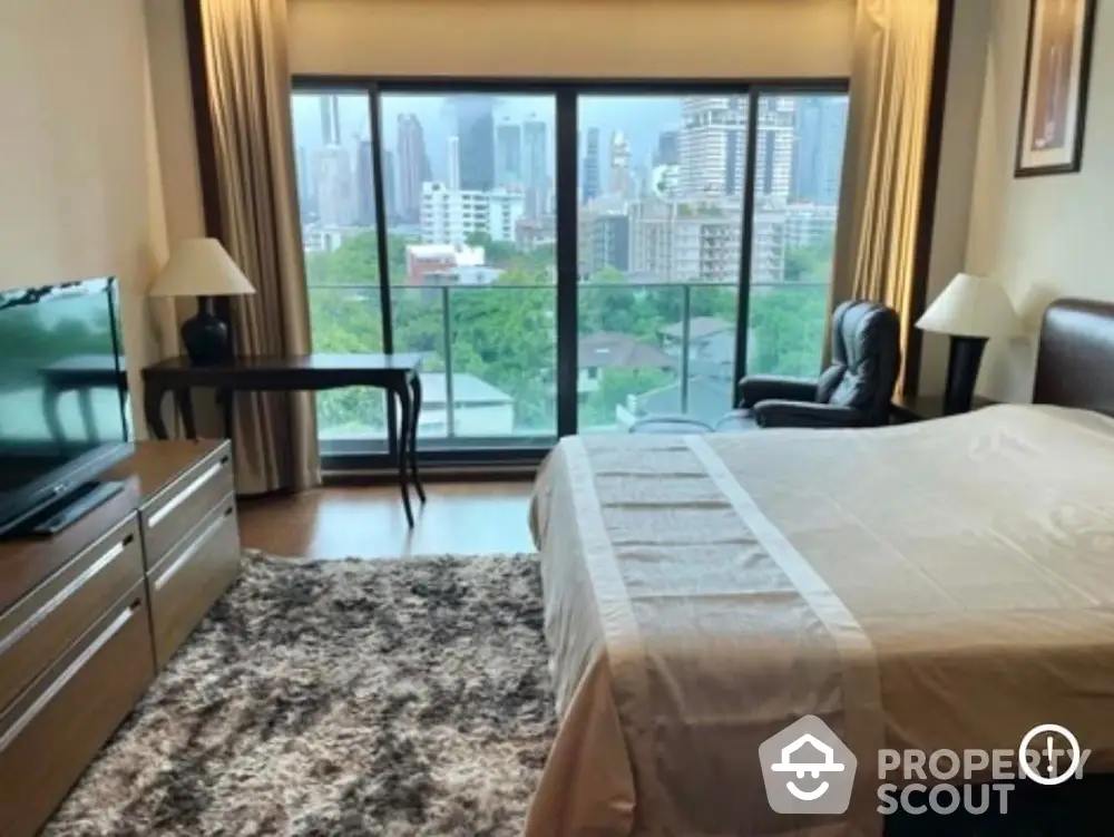 Spacious bedroom with city view and modern furnishings in high-rise apartment.