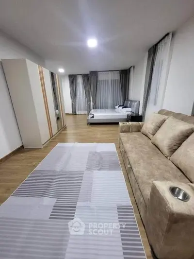 Spacious modern bedroom with cozy sofa and large windows