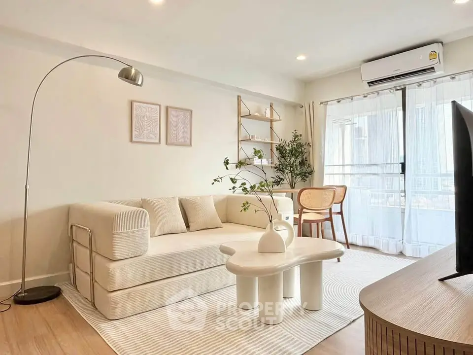 Modern living room with stylish decor, cozy sofa, and natural light from large windows.