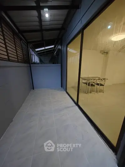 Spacious balcony with tiled flooring and glass sliding doors leading to dining area.