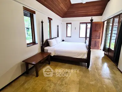 Spacious bedroom with elegant wooden bed and natural light in a serene setting.
