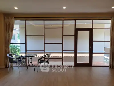 Spacious living room with large glass doors opening to a serene outdoor view, perfect for relaxation.
