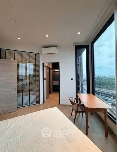 Modern bedroom with large windows offering stunning city views and elegant wooden furniture.