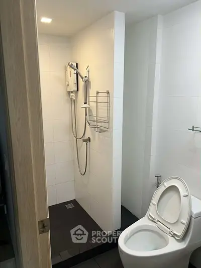 Modern bathroom with shower and toilet in sleek white tile design.