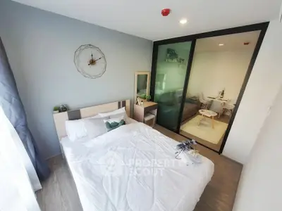 Modern bedroom with stylish decor and glass partition leading to a cozy living area.