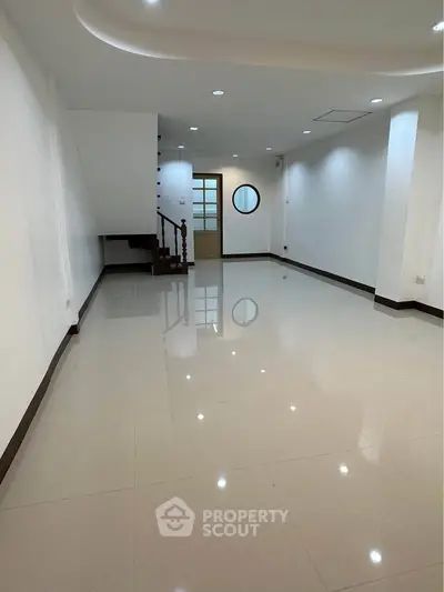 Spacious modern living room with glossy tiled floors and elegant staircase
