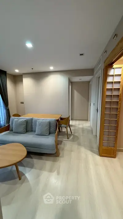 Modern living room with cozy seating and dining area, featuring elegant wooden accents and soft lighting.