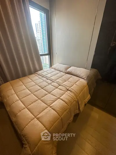 Cozy bedroom with city view, featuring a comfortable bed and large window for natural light.