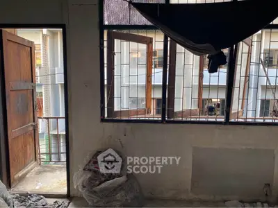 Spacious room with open windows and balcony access, ideal for renovation and customization.