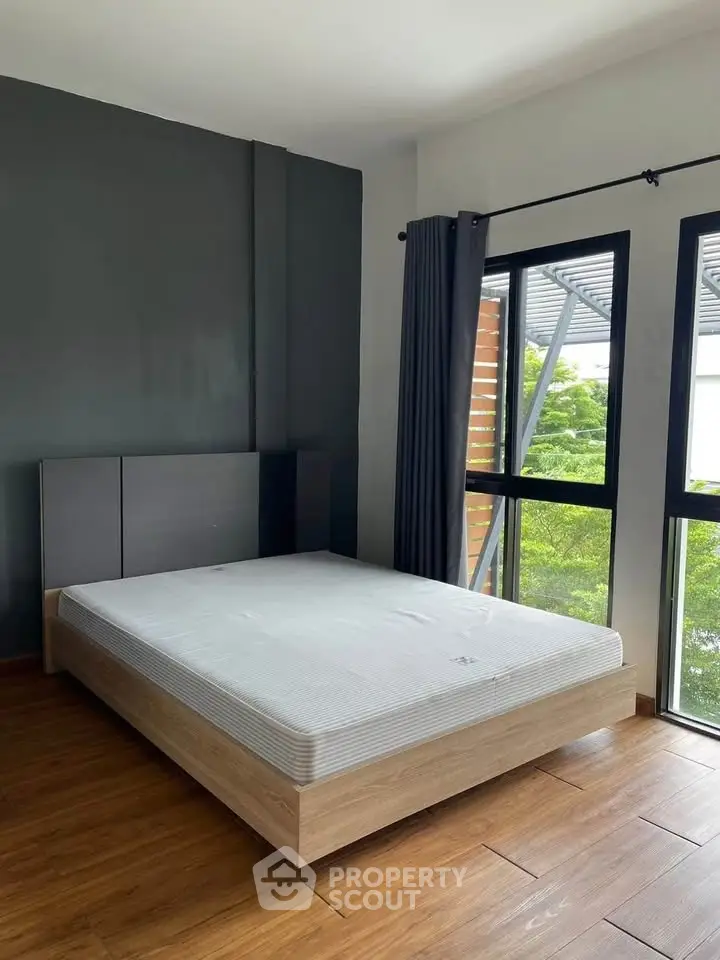 Modern bedroom with large windows and stylish wooden flooring