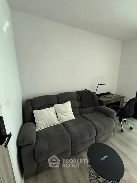Cozy living room with plush sofa and modern workspace setup, perfect for relaxation and productivity.