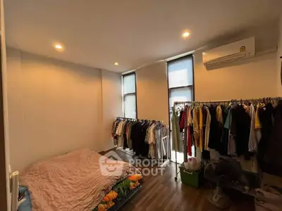 Cozy bedroom with wooden flooring, air conditioning, and ample closet space in modern apartment.