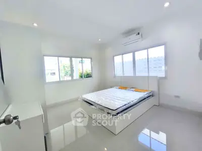 Bright and airy bedroom with large windows and modern air conditioning unit.
