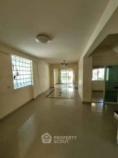 Spacious living room with large windows and tiled flooring, perfect for family gatherings.