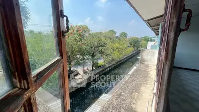 Charming balcony view overlooking a serene canal and lush greenery, perfect for relaxation.