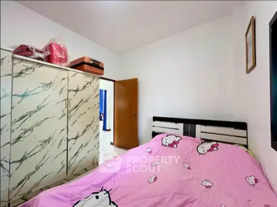 Cozy bedroom with stylish wardrobe and playful pink bedding, perfect for a comfortable living space.