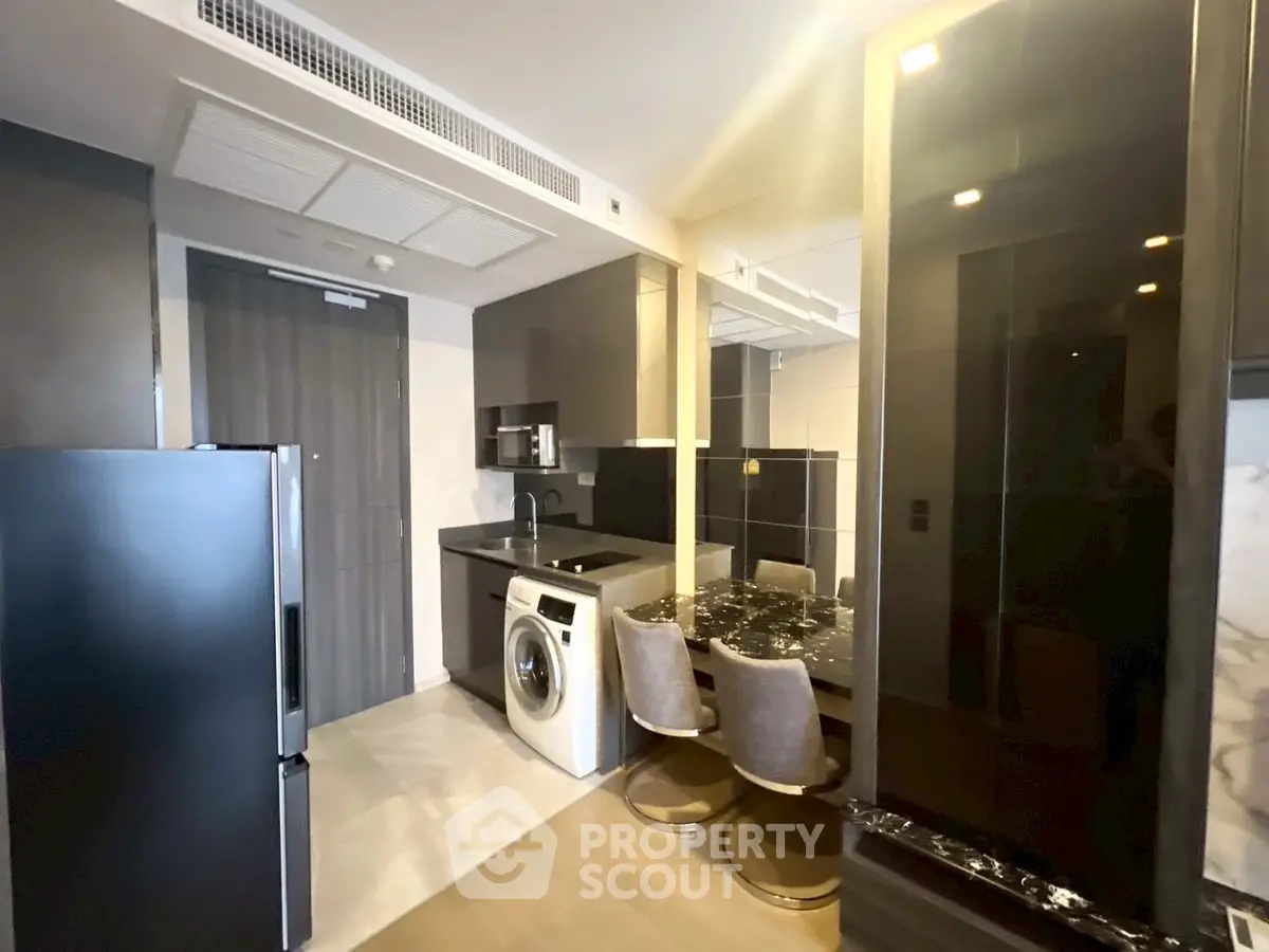 Modern kitchen with sleek appliances and washing machine in compact layout.