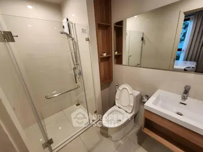 Modern bathroom with glass shower and sleek fixtures in contemporary apartment.