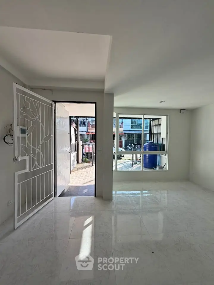 Bright and spacious living room with large windows and open entrance, perfect for modern living.