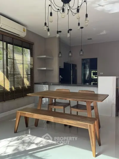 Modern dining area with wooden table and bench, stylish lighting, and large window.