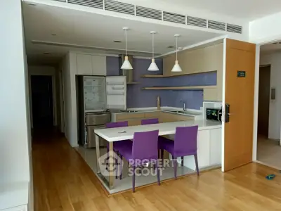 Modern kitchen with open layout and vibrant purple chairs in a stylish apartment.