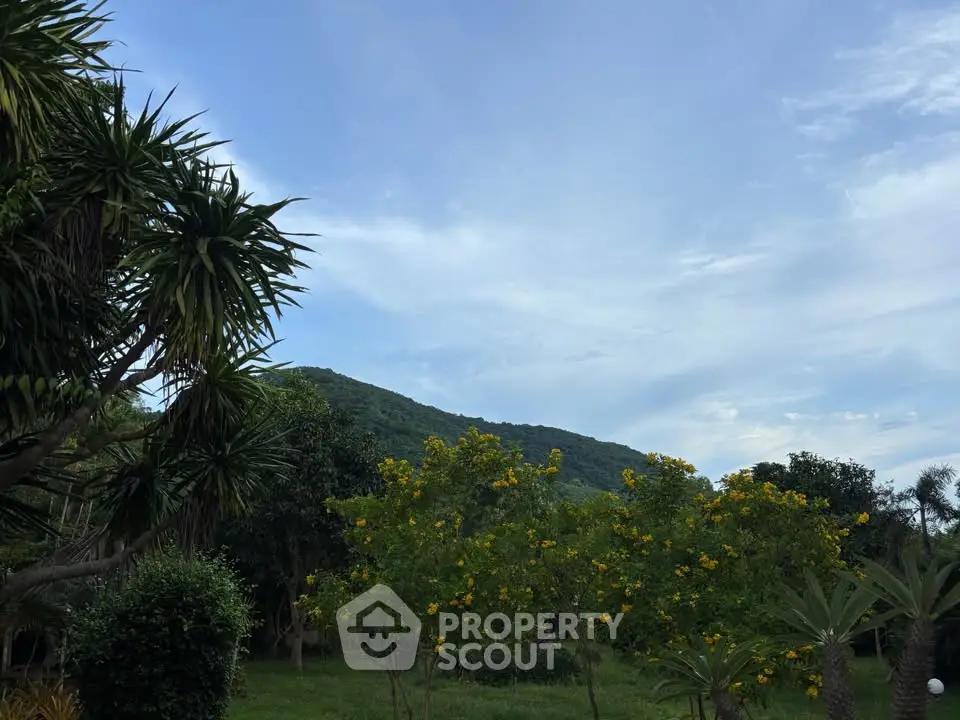 Scenic garden view with lush greenery and distant hills under a clear sky.