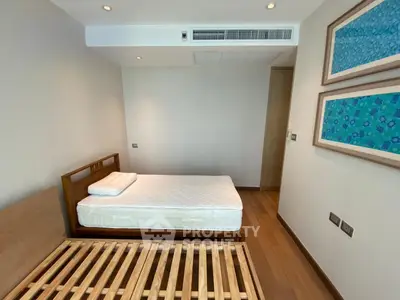 Spacious bedroom with wooden flooring and modern decor in a luxury apartment.